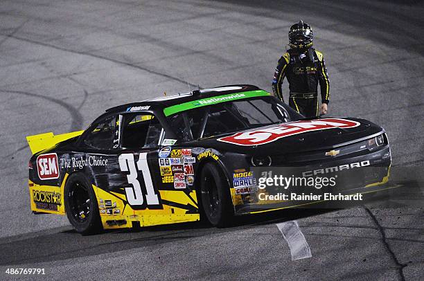Dylan Kwasniewski, driver of the Rockstar Chevrolet, stands next to his car after crashing during the NASCAR Nationwide Series ToyotaCare 250 at...