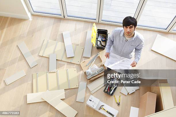 man surrounded by unassembled furniture - furniture instructions stock pictures, royalty-free photos & images