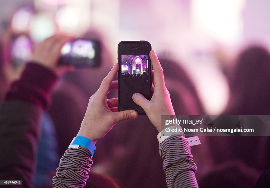 Fan snaps a photo with a phone at a concert