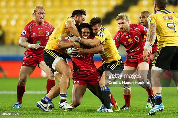 Ben Tapuai of the Reds is tackled by Jack Lam and Andre Taylor of the Hurricanes during the round 11 Super Rugby match between the Hurricanes and the...