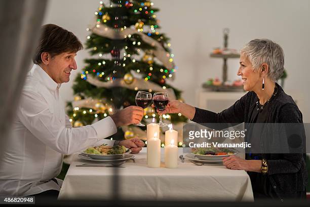 cheerful mature couple have christmas dinner - middle aged woman winter stockfoto's en -beelden