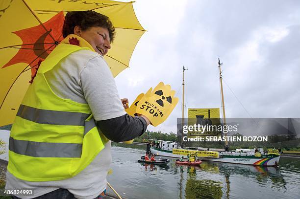 Militant for the Fessenheim nuclear powerplant closing salutes environmental group Greenpeace activists who hold from their Beluga II boat a banner...