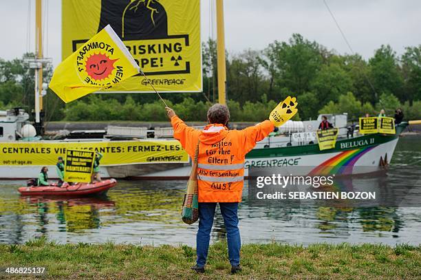 Militant for the Fessenheim nuclear powerplant closing salutes environmental group Greenpeace activists who hold from their Beluga II boat a banner...