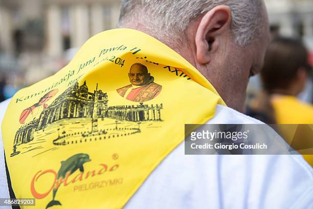 Pilgrim wears a scarf with pictures of John Paul II and John XXIII as he gathers in Saint Peter's Square on April 26, 2014 in Vatican City, Vatican....