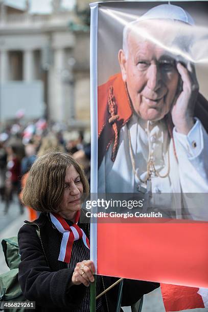 Pilgrim holds a banner picturing Pope John Paul II as she gathers in Saint Peter's Square on April 26, 2014 in Vatican City, Vatican. Dignitaries,...