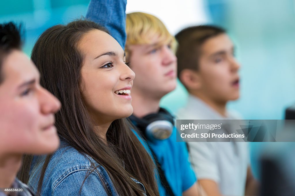 Teenage girl raising hand, asking question in high school class