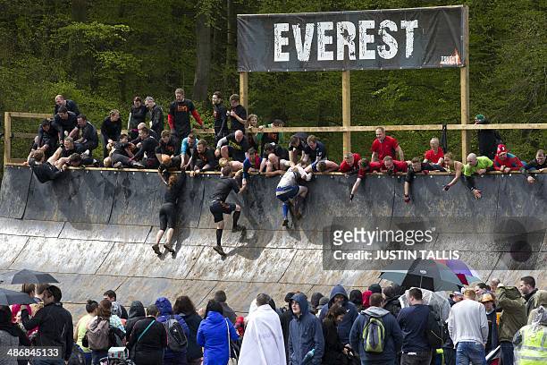 Participants make their way up the "everest" obsatcle during the Tough Mudder endurance race in Henley on Thames, West of London, on April 26, 2014....