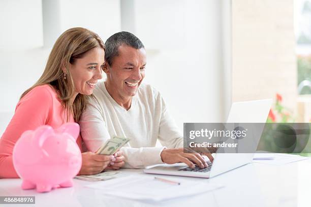 couple organizing their home finances - couple saving piggy bank stock pictures, royalty-free photos & images