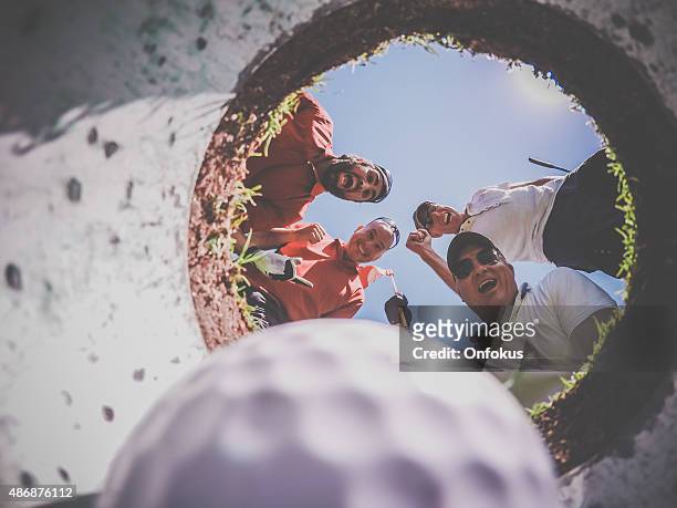 point of view golf players and ball from inside hole - golf ball hole stock pictures, royalty-free photos & images