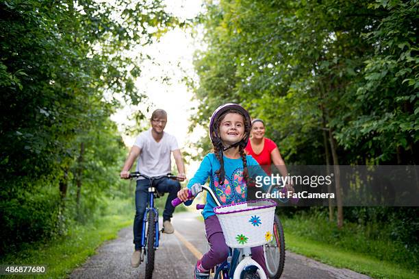 menina andando de bicicleta com seus pais - uma única flor - fotografias e filmes do acervo