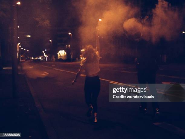 teenagers running down city street with smoke flares at night - rebel stock pictures, royalty-free photos & images