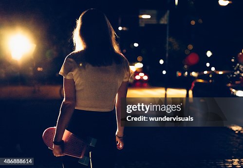 Skater girl walking alone with her skateboard at night Skater girl walking alone with her skateboard at night