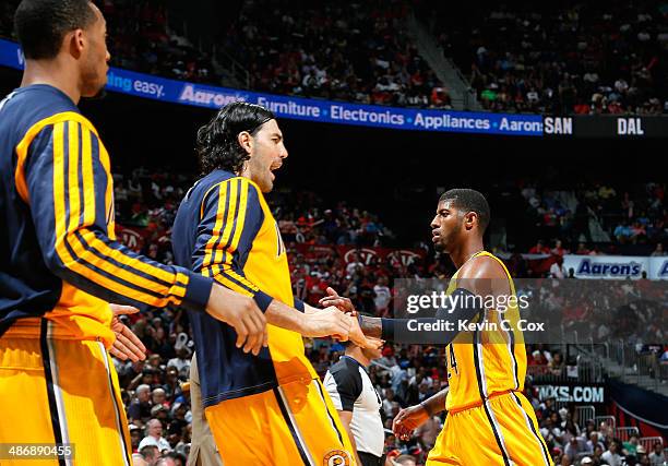 Paul George of the Indiana Pacers reacts after a basket against the Atlanta Hawks with Luis Scola and Evan Turner in Game Four of the Eastern...