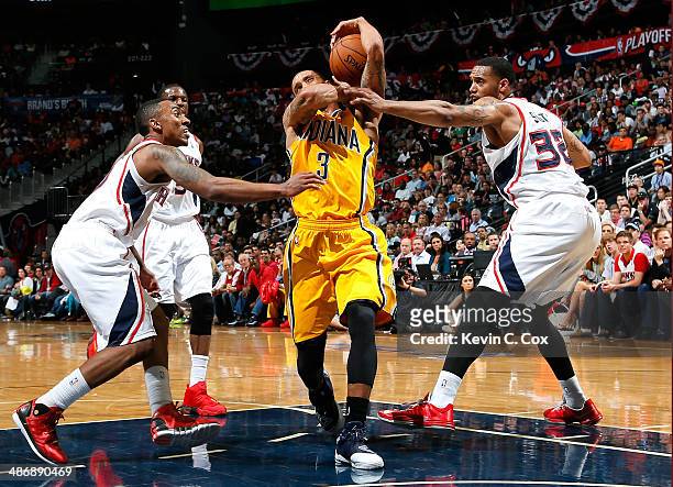 George Hill of the Indiana Pacers draws a foul from Mike Scott of the Atlanta Hawks as he drives to the basket in Game Four of the Eastern Conference...