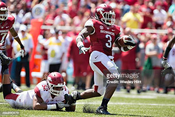 Alex Collins of the Arkansas Razorbacks Red squad is tackled from behind by Daunte Carr of the White squad during the Red White Spring Football game...
