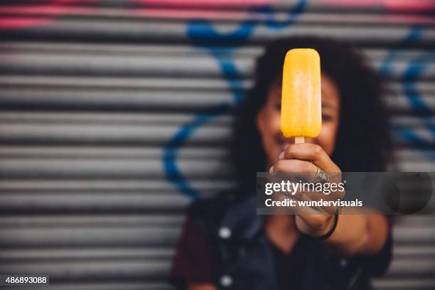 girl holding an ice lolly in front of her face - flavored ice 個照片及圖片檔