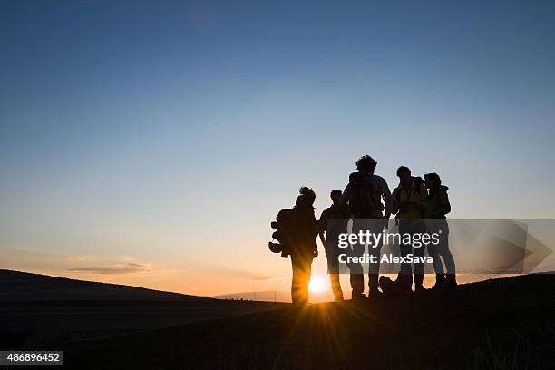 bunch of friends with backpacks at sunrise - silhouette meeting stock pictures, royalty-free photos & images