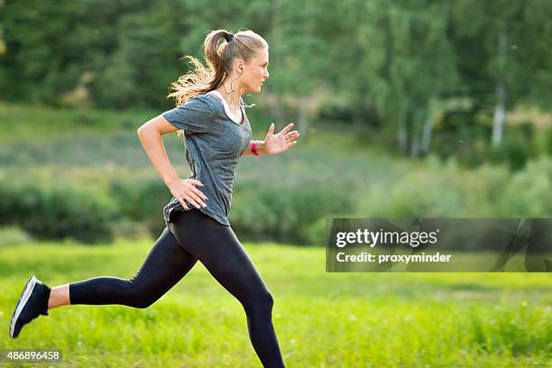 woman listening to music and running in park - youth culture speed stock pictures, royalty-free photos & images