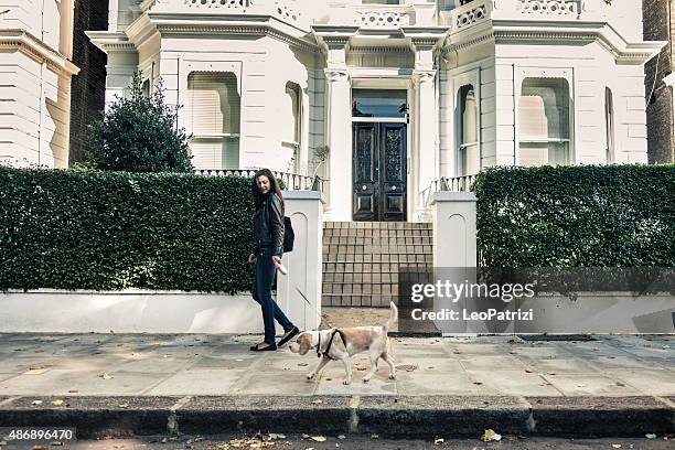 happy woman walking with dog in early sunday morning - notting hill street stock pictures, royalty-free photos & images