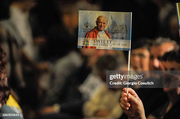 Pilgrims from Poland hold flags picturing Pope John Paul II as they attend a Mass celebration in the Church of Santa Agense in Agona, at Piazza...