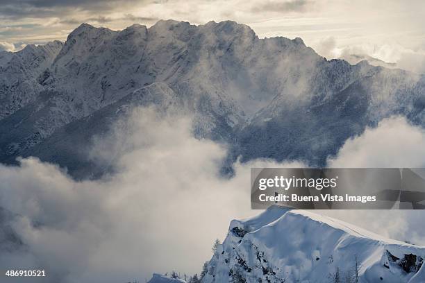 lone climber standing on a snowy peak - berggipfel stock-fotos und bilder