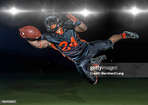 american football player jumping to catch football - catching football stock pictures, royalty-free photos & images