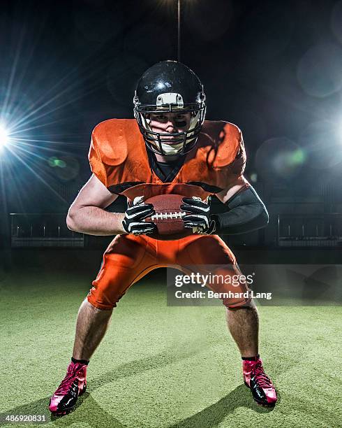 american football player holding ball out - football spieler stock-fotos und bilder