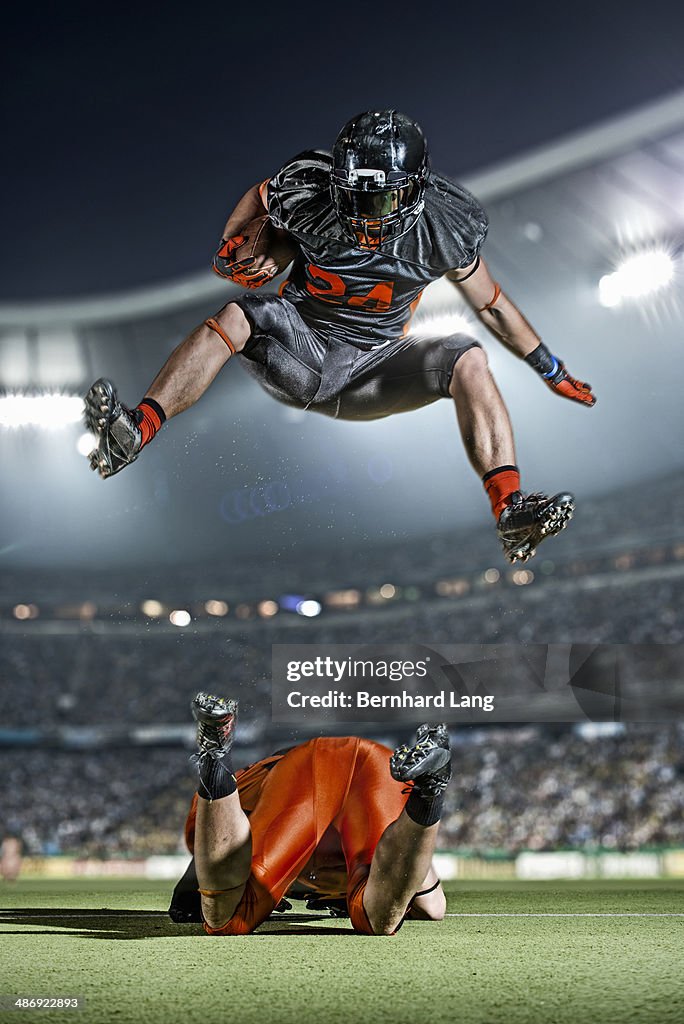 American football player jumping over opponent