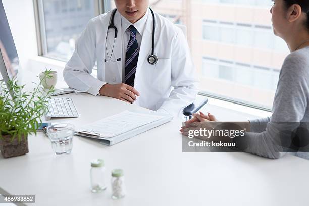 doctor discussing with female patient in clinic - puke japan stock pictures, royalty-free photos & images