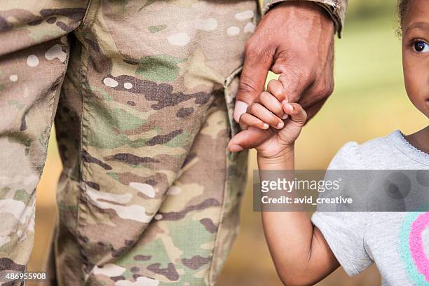 young girl holds soldier daddy's finger - armed forces stock pictures, royalty-free photos & images
