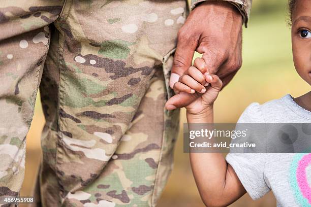 young girl holds soldier daddy's finger - people in military uniform stock pictures, royalty-free photos & images