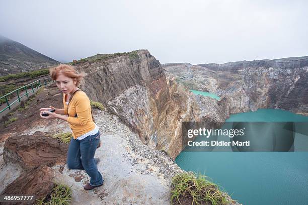 Young woman walking along the rim of Kelimutu volcano in Flores, Indonesia