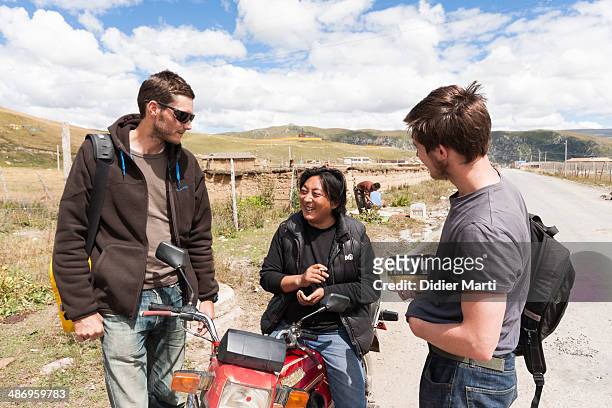 Two travellers asking questions to a local man in the countryside of Sichuan province in China