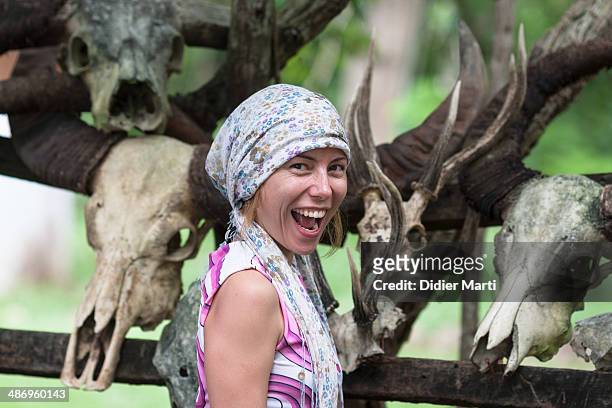 Young woman smiling in front of animals skulls in Komodo Island, famous for the dragons, Indonesia