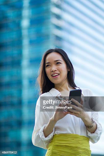 attractive asian woman with mobile phone - marina bay - singapore stock pictures, royalty-free photos & images