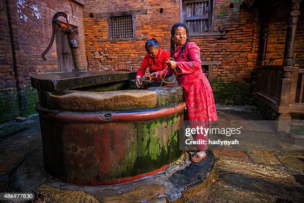 nepali mujeres conseguir agua desde el bien de bhaktapur - pozo agua fotografías e imágenes de stock
