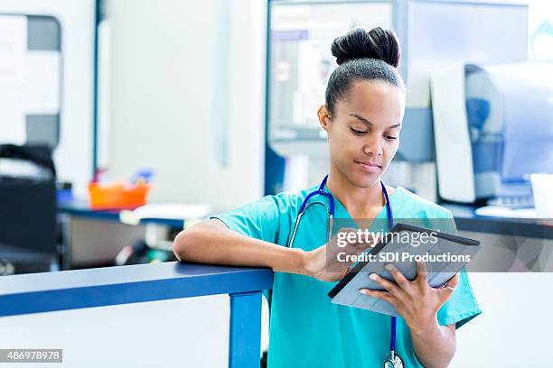 nurse updating digital patient charts in modern emergency room - nurse ipad stockfoto's en -beelden