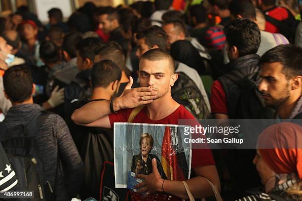 Migrant from Syria holds a picture of German Chancellor Angela Merkel as he and approximately 800 others arrive from Hungary at Munich Hauptbahnhof...