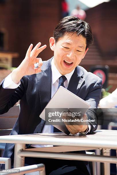 japanese businessman makes excellent sign while on tablet conference outdoors - super excited suit stock pictures, royalty-free photos & images