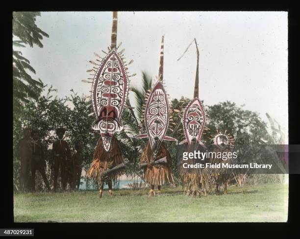 Four men performing and wearing semese masks, Papua New Guinea, March 1911. These are masks of a type worn during the hevehe ceremonial cycle and are...