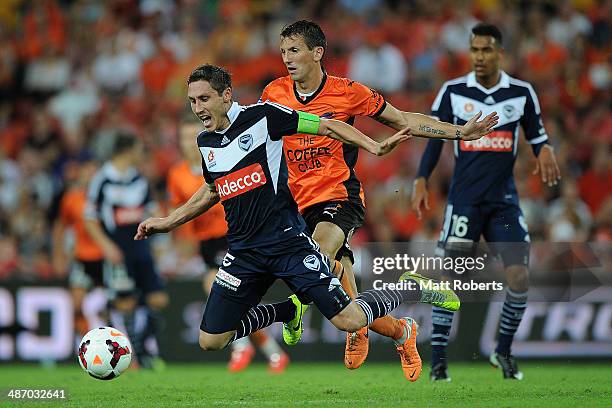 Mark Milligan of the Victory is tackled by Liam Miller of the Roar during the A-League Semi Final match between the Brisbane Roar and Melbourne...