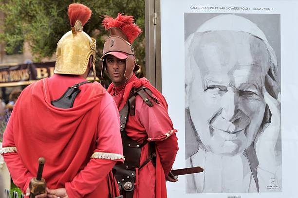 Men dressed in centurion stand by a portrait of Pope John Paul II in Rome, as the canonisation mass of Popes John XXIII and John Paul II takes place...