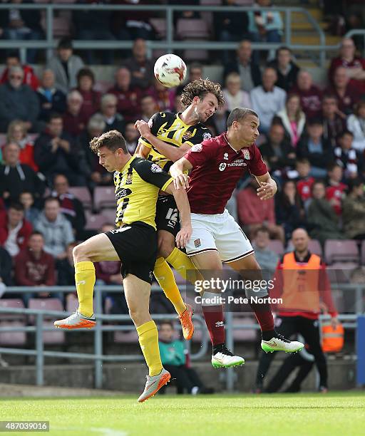 Christian Doidge and Matt McClure of Dagenham & Redbridge contest the ball with Rod McDonald of Northampton Town during the Sky Bet League Two match...