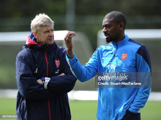 Arsenal manager Arsene Wenger talks with Abou Diaby during a training session at London Colney on April 27, 2014 in St Albans, England.