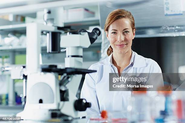 portrait of smiling female scientist - cientifico con microscopio fotografías e imágenes de stock