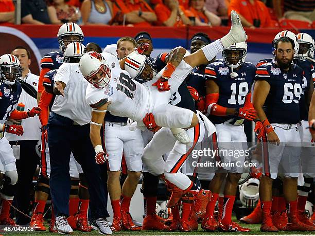 Cole Hikutini of the Louisville Cardinals fails to pull in a reception as he is tackled by Tray Matthews of the Auburn Tigers at Georgia Dome on...