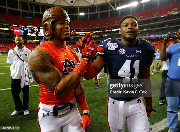 Tray Matthews of the Auburn Tigers wears the old leather helmet trophy as he celebrates their 31-24 win over the Louisville Cardinals with Jordan...