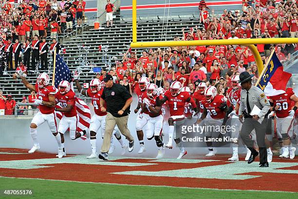Head Coach Dave Doeren of the North Carolina State Wolfpack leads his team onto the field prior to their game against the Troy Trojans at...