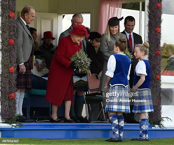 Posy of heather is presented to Queen Elizabeth ll as she attends the Breamar Highland games with Prince Philip, Duke of Edinburgh, Prince Charles,...