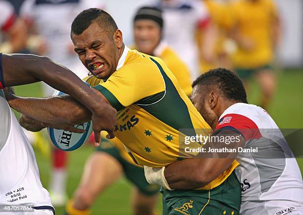 Kurtley Beale of the Australia Wallabies tries to fight his way between two United States Eagles players during a match at Soldier Field on September...